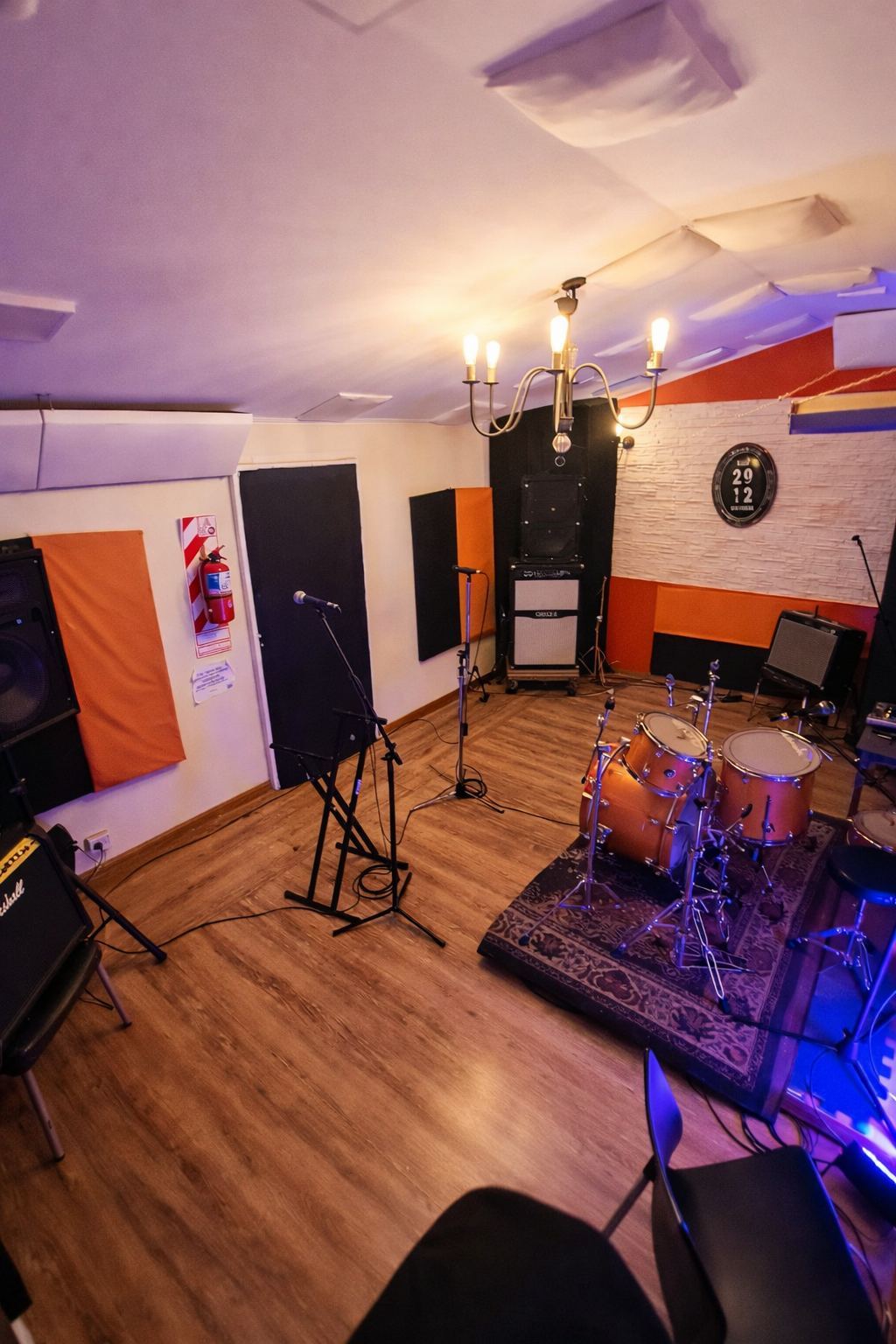 Sala de ensayo con luz cálida, batería y amplificadores